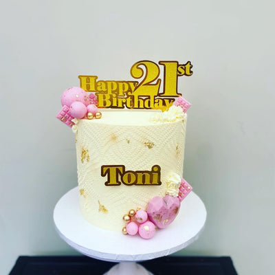 Cream buttercream cake with gold and pink decorations