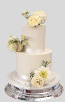 A two-tier fondant wedding cake with white icing and decorated with fresh flowers.