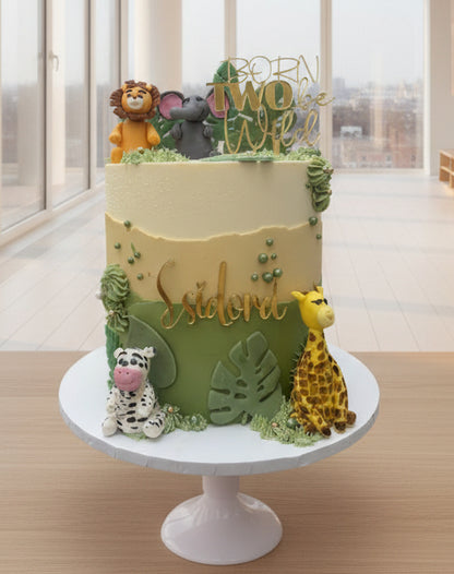 Decorative cake with animal figures and greenery on a white surface