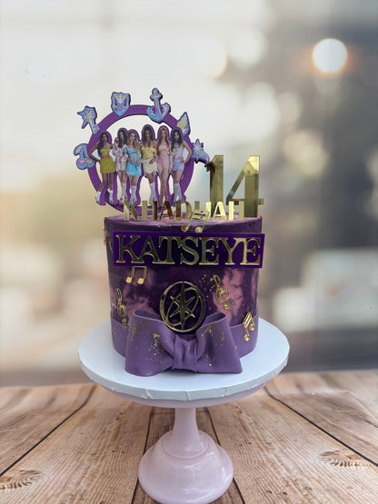 Decorative purple cake with 'Katseye' branding on a wooden surface
