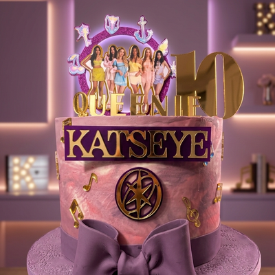 Decorative cake with 'Katseye' and 'Queen' text, featuring a bow and colorful design.